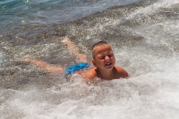 短髪の9歳の男の子が海で泳いで夏に波と遊ぶ — ストック写真