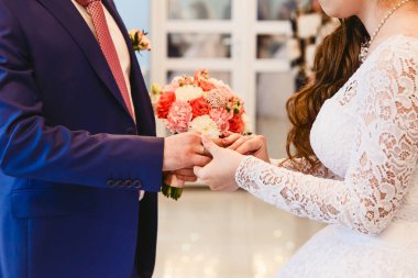 Yeni evliler birbirlerinin yüzüklerini yakın takarlar.