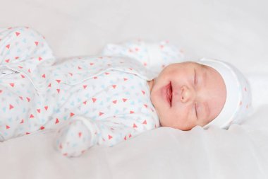 Yeni doğan bebek doğumdan iki hafta sonra uykusunda güler..