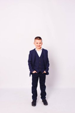 Beyaz arka planda mavi üniformalı yakışıklı bir çocuk.