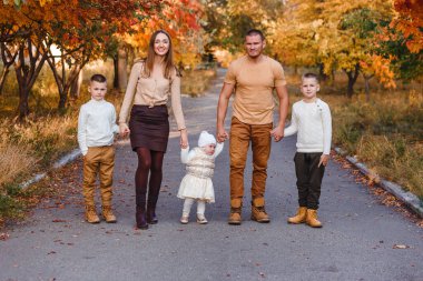 Sonbaharda yürüyüş yapan beş kişilik mutlu bir aile dağ külünün sarı arka planına karşı