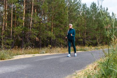 Emeklilik yaşındaki zayıf bir kadın parkta yürüyen İskandinav bir kadınla meşgul..