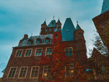 Sonbaharda mavi gökyüzüne karşı Cochem kasabasında bir dağ yamacında bir ortaçağ şatosu