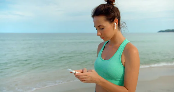 woman texting a massage on the smartphone, she walks outdoors the beach and chatting via whats up