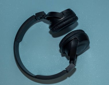 Mavi arka planda kablosuz siyah kulaklık..