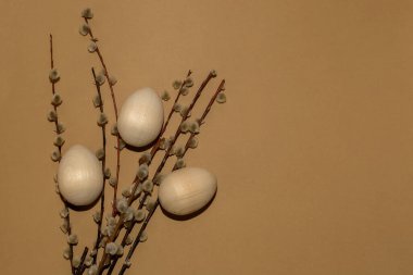 Kahverengi arka planda söğüt dalları ve boyanmamış ahşap yumurtalar. Paskalya.