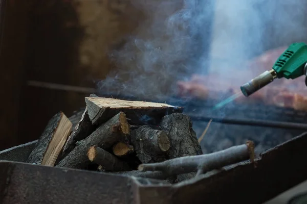 Kindling palivové dřevo pro smažení masa s plynovým zapalovačem. — Stock fotografie