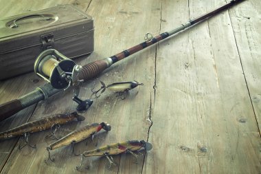 Antique Fishing Rod and Lures on a Grunge Wood Surface clipart