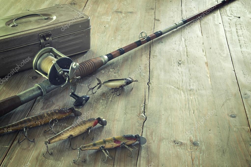 Antique Fishing Rod and Lures on a Grunge Wood Surface Stock Photo
