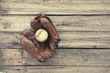 Old leather baseball mitt and ball on grunge wood background clipart