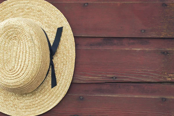 Il cappello di paglia di Amish uomo pende su una porta rossa fienile — Foto Stock