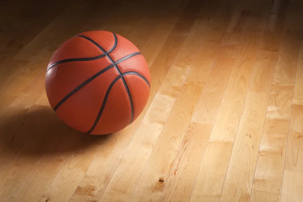 Baloncesto en el piso de la cancha de madera dura con iluminación puntual — Foto de Stock