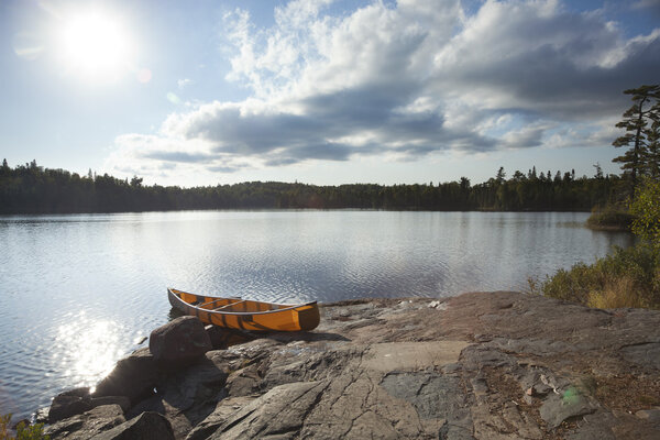 Orange canoe on rocky shore of Boundary Waters lake near sundown