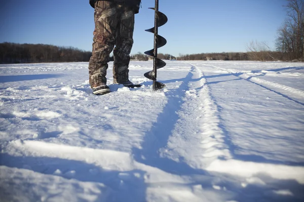 Ice fisherman borrar hål med skruv på lake i Minnesota — Stockfoto