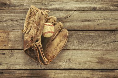 Old baseball and mitt on rough wood background clipart
