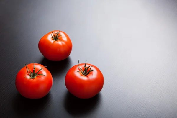 Tres tomates rojos maduros sobre la mesa . — Foto de Stock