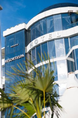 Otelin, tatil köyünün ve kaplıcanın dışı. Sahilde palmiye ağaçlarından yapılmış modern bir bina.