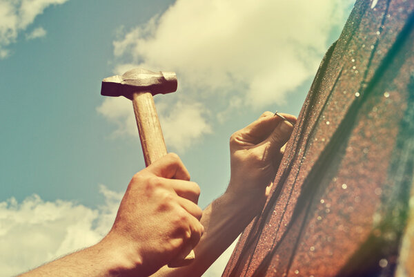 Workers hands with hammer, roof repairs