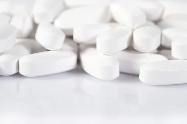 Heap of white pills on a white — Stock Photo, Image