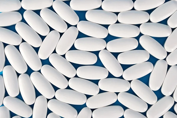 Vista superior de las píldoras blancas en un azul — Foto de Stock