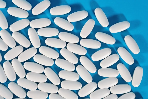 Top view of white pills on a blue — Stock Photo, Image