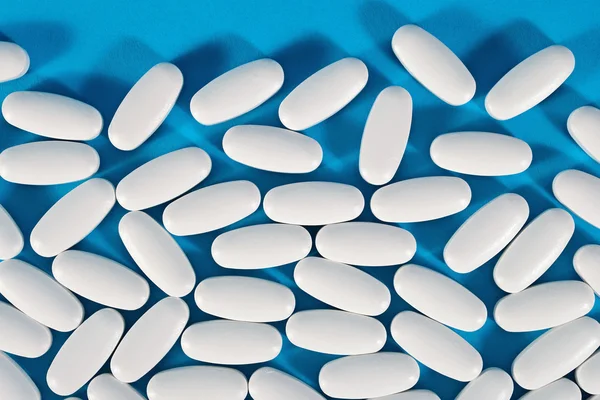 Top view of white pills on a blue — Stock Photo, Image