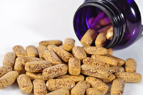 Pills spill out from bottle on a white — Stock Photo, Image