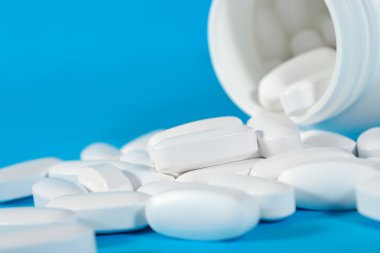 Şişe mavi üzerinde dışarı beyaz hap sızıntısı