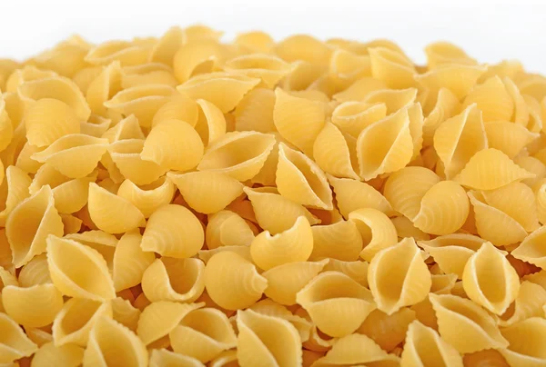 Heap of uncooked italian pasta shells on a white — Stock Photo, Image