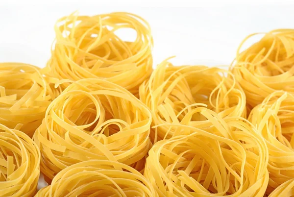 Tagliatelle di pasta italiana cruda nidi su un bianco — Foto Stock