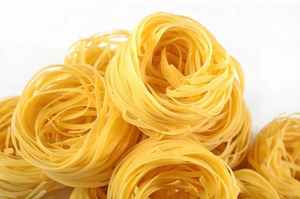 Tagliatelle di pasta italiana cruda nidi su un bianco — Foto Stock