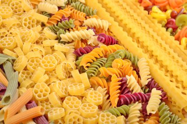 Assortment of colored uncooked Italian pasta close up clipart