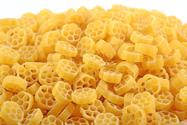 Un mucchio di rotelle di pasta italiana cruda su un bianco — Foto Stock