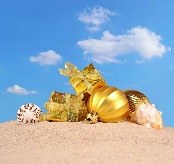 Adornos navideños y conchas marinas en una playa de arena — Foto de Stock