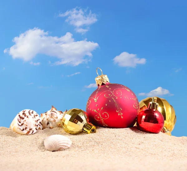 Adornos navideños y conchas marinas en una playa de arena — Foto de Stock