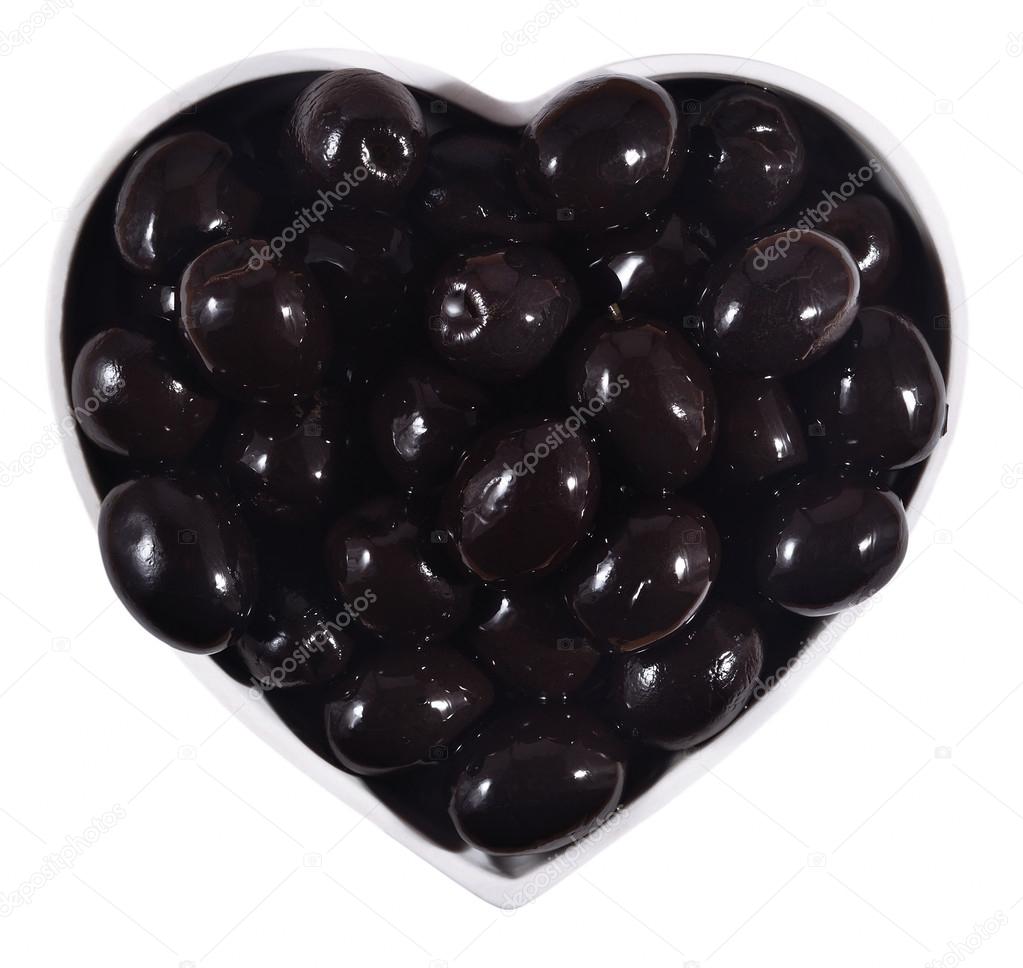 Black olives in plate in the form of heart on a white