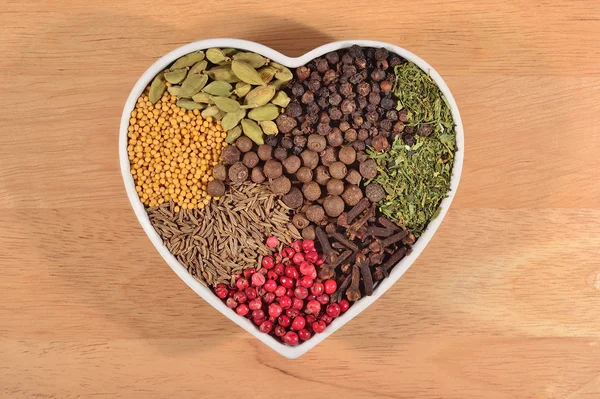 Different dry spices in plate in form of heart — Stock Photo, Image