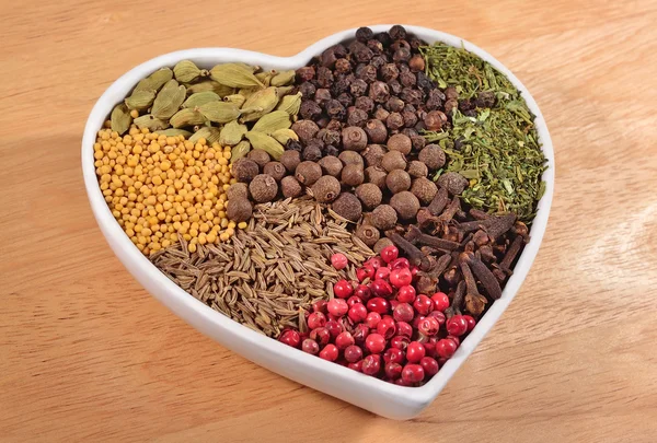 Different dry spices in plate in form of heart — Stock Photo, Image