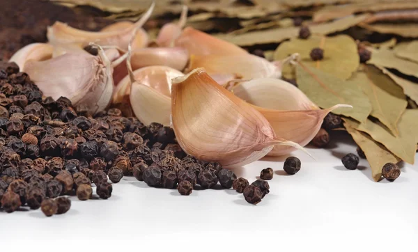 Garlic, bay leaves and peppercorns on a white — Stock Photo, Image