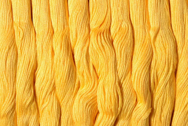 Yellow skeins of floss as background texture — Stock Photo, Image