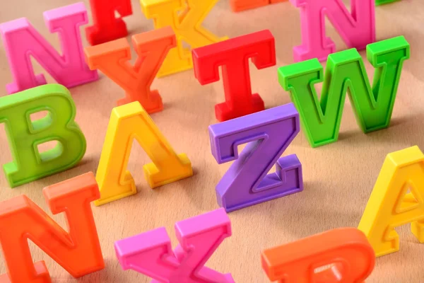 Plastic colorful letters close up on a wooden background — Stock Photo, Image