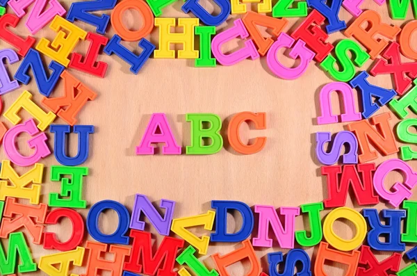 Kunststof gekleurde letters Abc op een houten achtergrond — Stockfoto