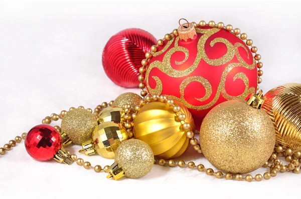 在一张白纸的金色和红色圣诞装饰品 免版税图库照片