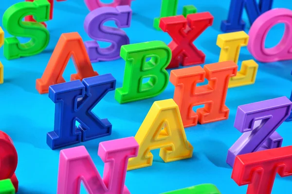 Пластикові барвисті літери алфавіту на синьому фоні — стокове фото