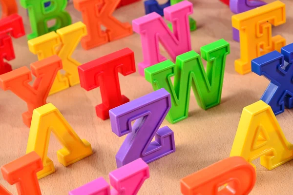 Kunststof kleurrijke Alfabetletters op een houten achtergrond — Stockfoto