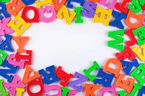 Marco de letras de alfabeto colorido plástico en un blanco —  Fotos de Stock