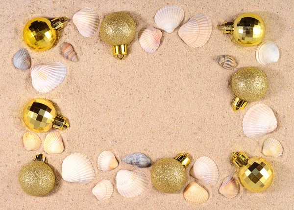 Gyllene juldekorationer och snäckskal på en sandstrand — Stockfoto