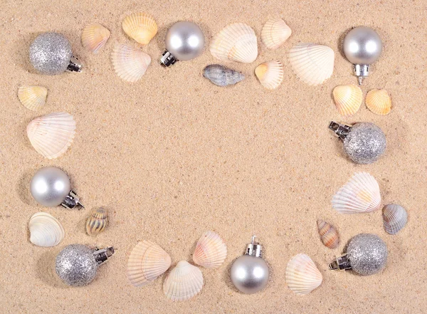 Silver Christmas decorations and seashells on a beach sand — Stock Photo, Image