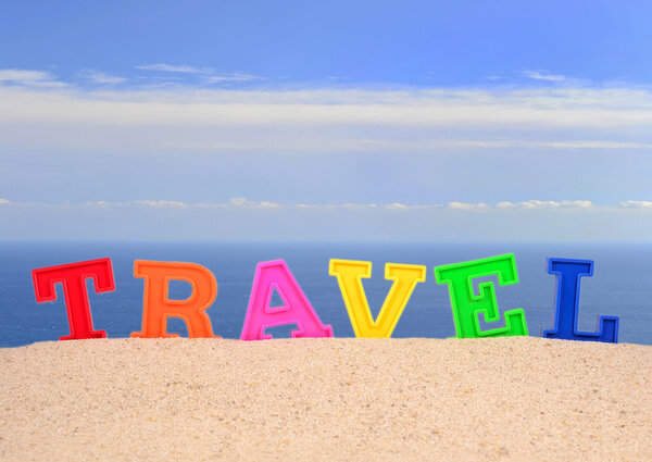 Travel letters on a beach sand against the background of the sea