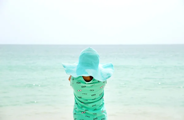 Rozkošná holčička nosit klobouk stojící na pláži během letních prázdnin — Stock fotografie